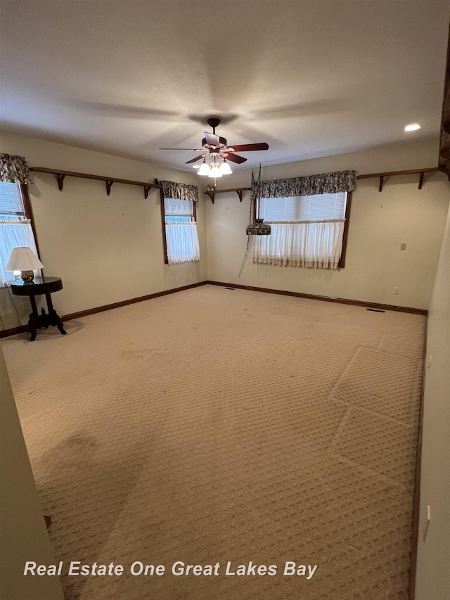 carpeted spare room with ceiling fan