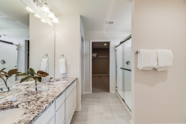 bathroom with walk in shower, vanity, and tile patterned flooring