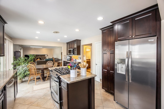 kitchen featuring light stone counters, light tile patterned floors, stainless steel appliances, and dark brown cabinetry