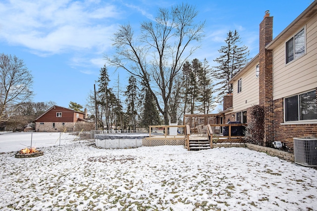 yard layered in snow featuring cooling unit and a wooden deck