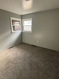 spare room featuring dark colored carpet