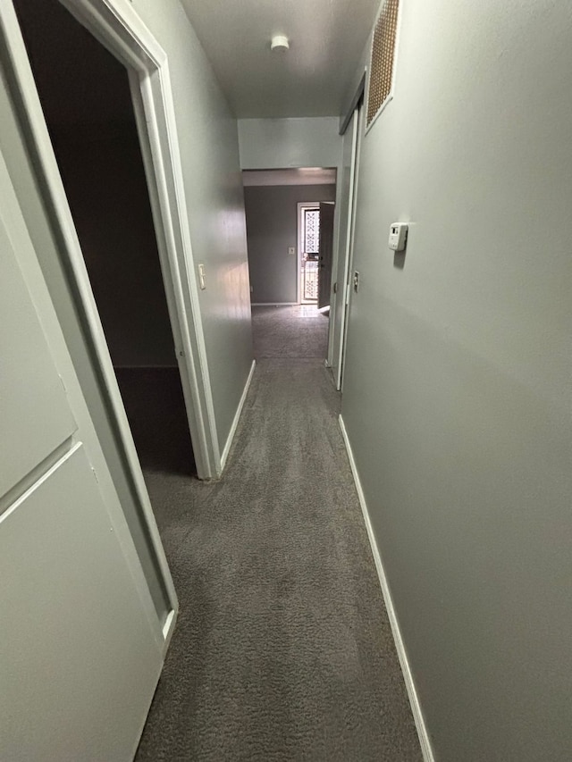 corridor featuring dark colored carpet