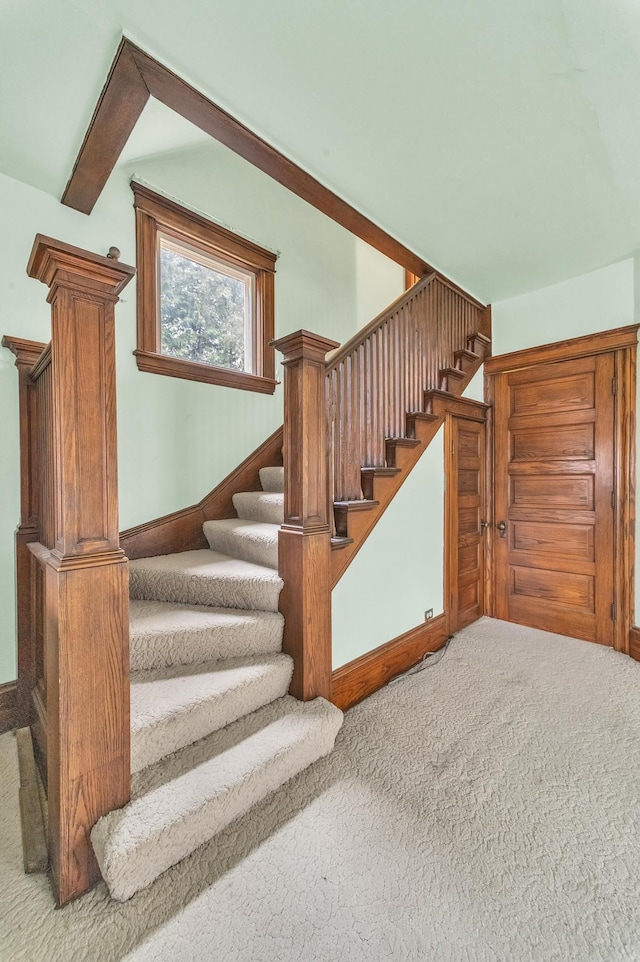 stairs featuring carpet flooring and beamed ceiling