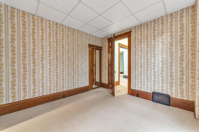 carpeted empty room featuring a drop ceiling