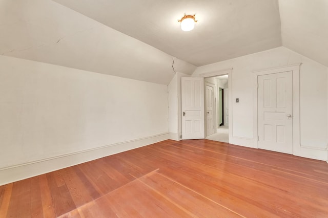 additional living space featuring wood-type flooring and vaulted ceiling