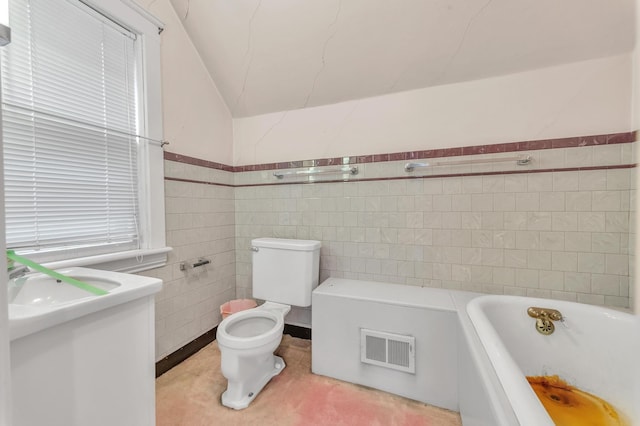 bathroom featuring lofted ceiling, vanity, tile walls, toilet, and a bathing tub