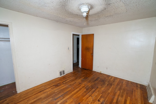 unfurnished bedroom featuring a closet, dark hardwood / wood-style flooring, and a textured ceiling