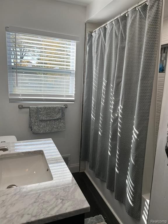 bathroom featuring baseboards, shower / bath combination with curtain, and vanity