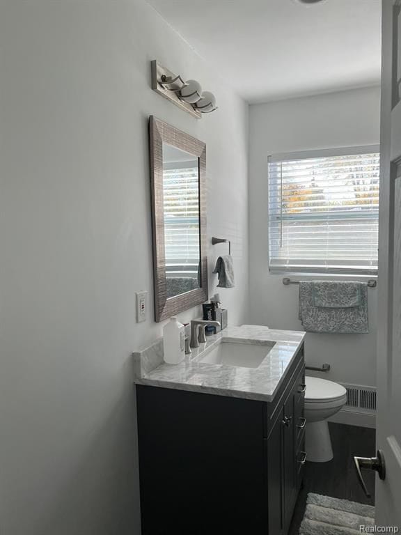 bathroom featuring plenty of natural light, vanity, toilet, and wood finished floors