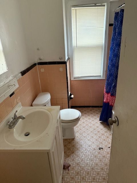 bathroom with vanity, a healthy amount of sunlight, tile walls, and toilet