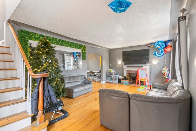 living room featuring hardwood / wood-style floors, a textured ceiling, and a brick fireplace