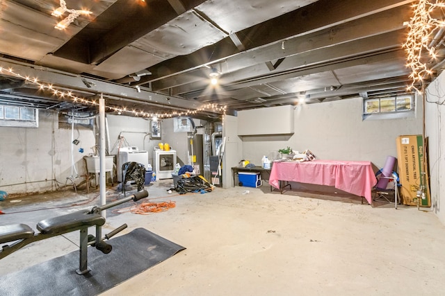 basement featuring washing machine and dryer, sink, a wealth of natural light, and water heater