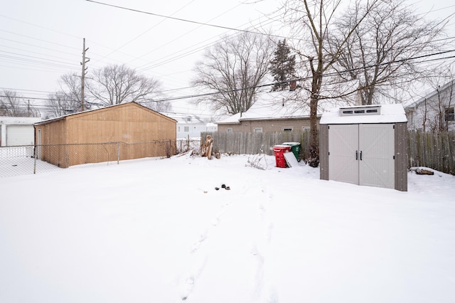 snowy yard featuring a storage unit