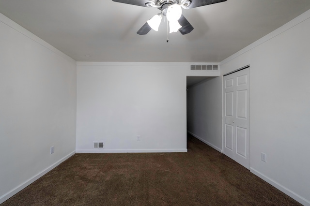 empty room with crown molding, ceiling fan, and dark colored carpet