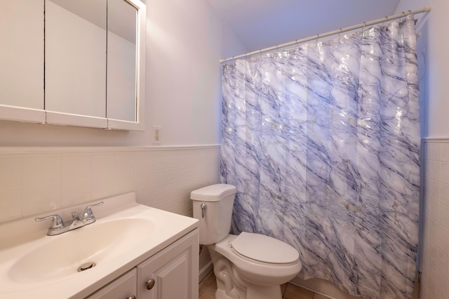 bathroom featuring tile walls, vanity, and toilet