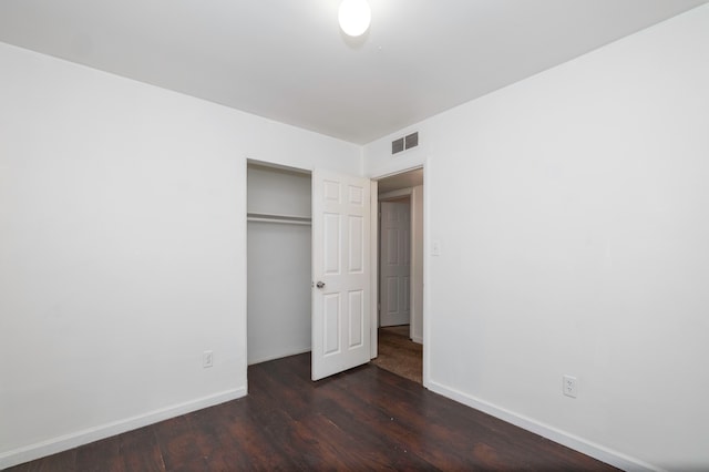 unfurnished bedroom featuring dark hardwood / wood-style flooring and a closet