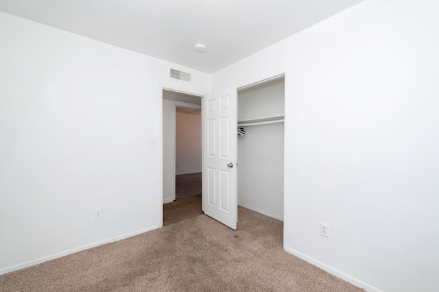 unfurnished bedroom with light colored carpet and a closet