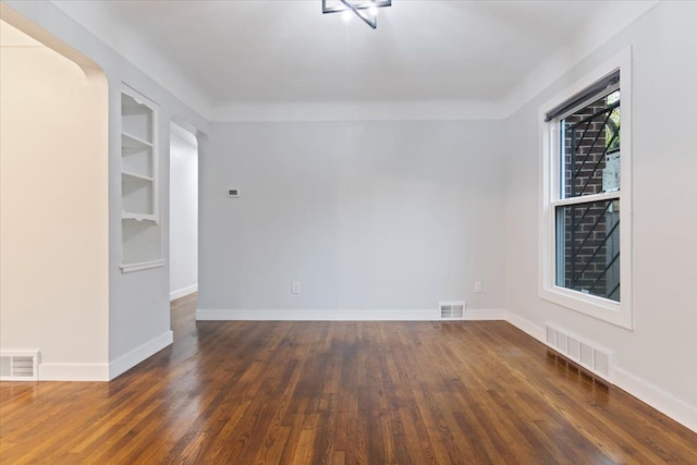 spare room with dark wood-type flooring and built in features