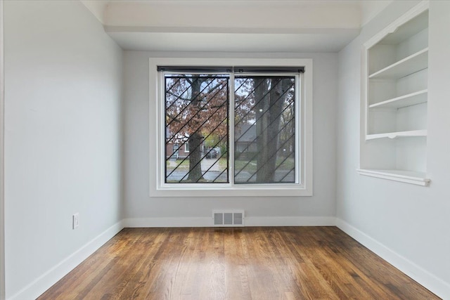 unfurnished dining area featuring hardwood / wood-style floors and built in features