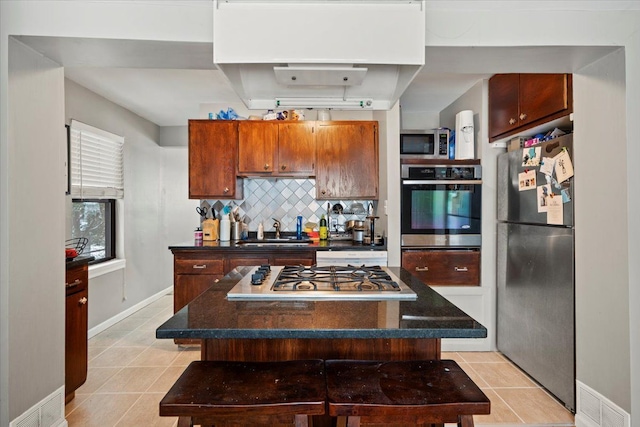 kitchen with appliances with stainless steel finishes, sink, a breakfast bar, and a center island