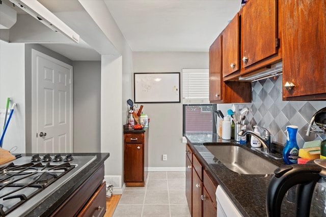 kitchen featuring dark stone countertops, sink, backsplash, stainless steel gas cooktop, and light tile patterned floors