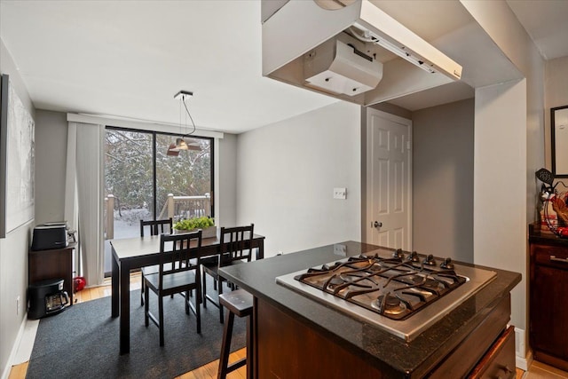 kitchen with pendant lighting, stainless steel gas cooktop, a breakfast bar area, and light wood-type flooring