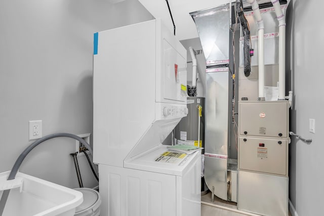 utility room featuring sink, stacked washer / dryer, and heating unit