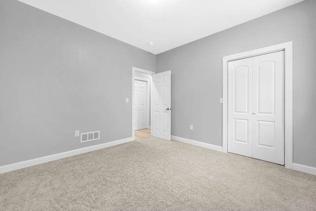 unfurnished bedroom with a closet and light colored carpet