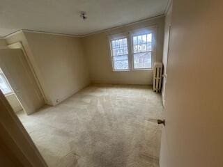 empty room with radiator and light colored carpet