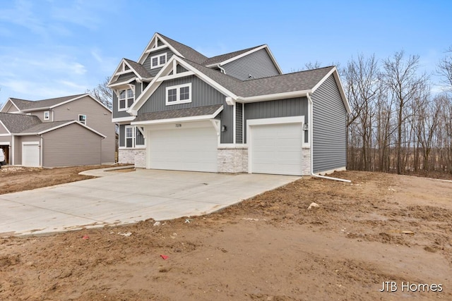 craftsman-style home with board and batten siding, roof with shingles, and driveway