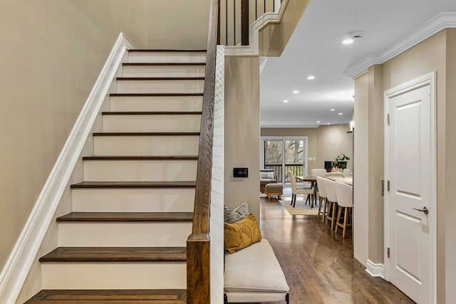 stairway with crown molding and hardwood / wood-style floors