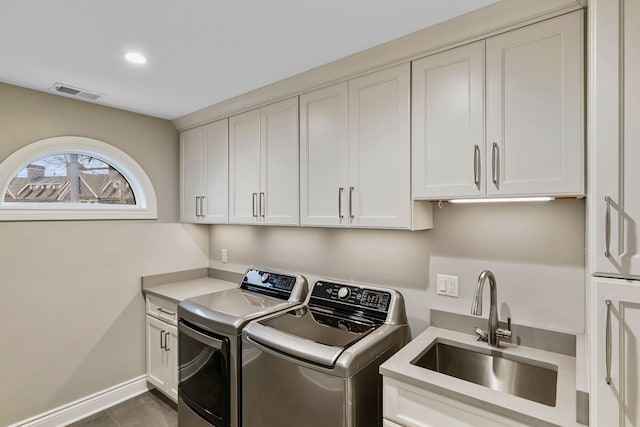 clothes washing area featuring washer and clothes dryer, cabinets, dark tile patterned floors, and sink