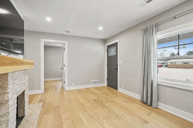 foyer with light hardwood / wood-style flooring and a stone fireplace