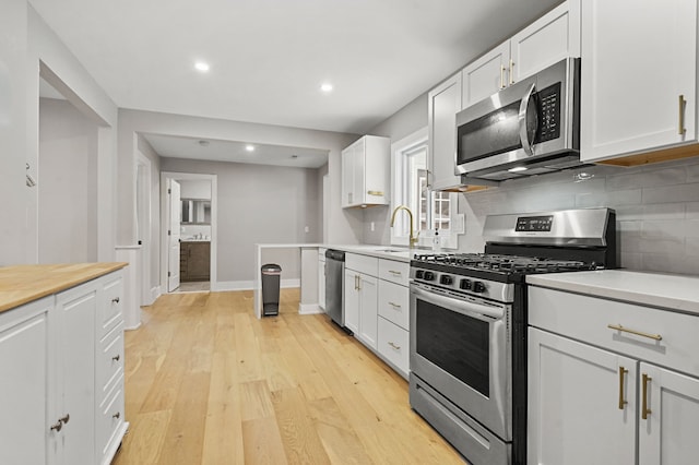 kitchen featuring sink, backsplash, white cabinets, and stainless steel appliances