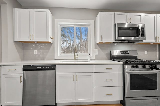 kitchen featuring appliances with stainless steel finishes, white cabinets, tasteful backsplash, and sink