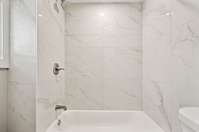 bathroom featuring toilet and tiled shower / bath