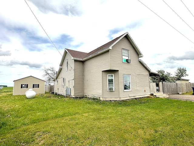 rear view of property with a lawn and a storage shed