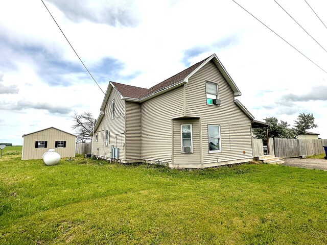 back of property featuring a lawn and a storage unit