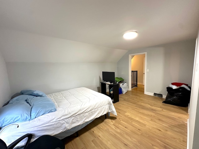 bedroom with vaulted ceiling and light wood-type flooring