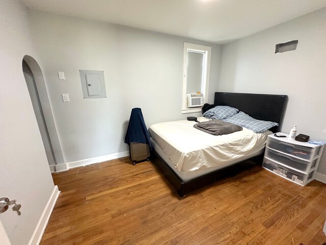 bedroom featuring hardwood / wood-style floors, electric panel, and cooling unit