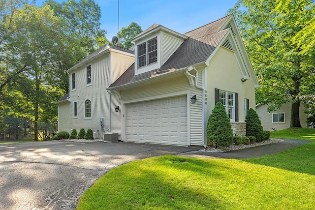 view of front of house with central AC unit, a garage, and a front lawn