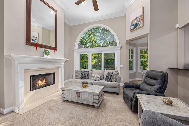 living room with ceiling fan, a high end fireplace, light colored carpet, and ornamental molding