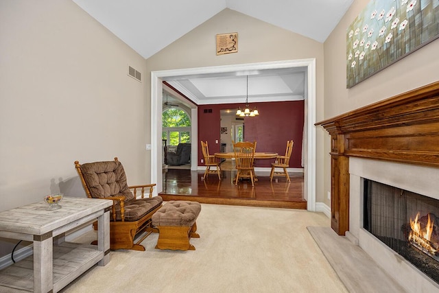 living area with light colored carpet, lofted ceiling, and an inviting chandelier