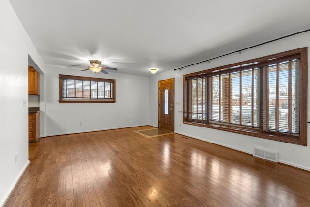 unfurnished living room with wood-type flooring, ceiling fan, and a healthy amount of sunlight