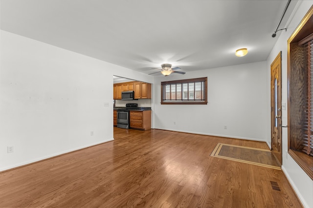 unfurnished living room featuring ceiling fan, rail lighting, and hardwood / wood-style flooring