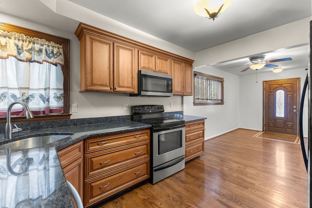 kitchen featuring appliances with stainless steel finishes, a healthy amount of sunlight, sink, and wood-type flooring