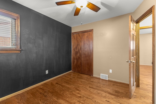 unfurnished bedroom featuring light wood-type flooring, ceiling fan, and a closet