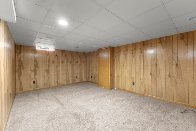 basement featuring light colored carpet and wood walls