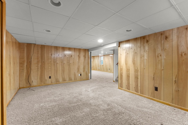 basement with carpet floors, wooden walls, and a drop ceiling