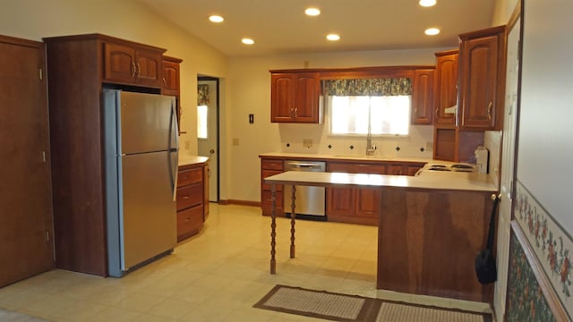 kitchen featuring kitchen peninsula, stainless steel appliances, vaulted ceiling, and sink